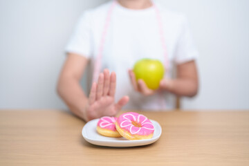 woman hand hold green Apple and reject donut, female fitness choose between fruit is Healthy and...