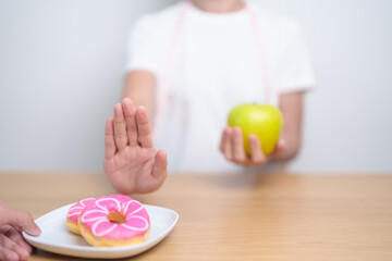 woman hand hold green Apple and reject donut, female fitness choose between fruit is Healthy and...