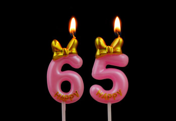 Burning pink birthday candles with gold bow and word happy isolated on black background, number 65.