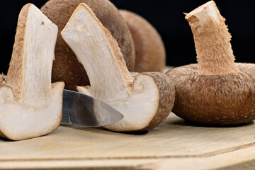 Shiitake mushrooms on cutting board over dark background