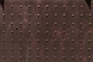 Rusty steel plate with pattern of rivets 
