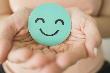 Hand holding green happy smile face paper cut, mental health assessment, child positive wellness,...