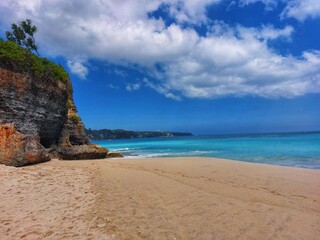 beach with a combination of blue water and sky, as well as decorated sand and stones