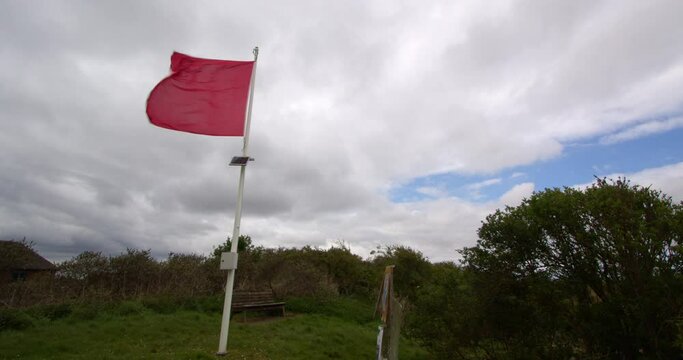 red danger flag flying in blustery wind left of frame