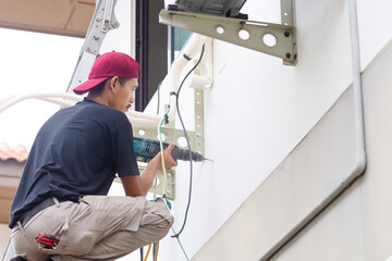 Technician man with hammer drill installing an air conditioning, Repairman service for repair and...