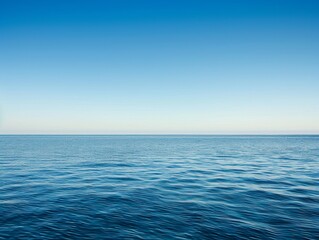 Obraz premium A vast expanse of clear blue sky meets the sparkling ocean, with fluffy white clouds drifting overhead