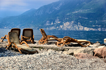 Empty Lounge Chairs Before the Start of the Holiday Season on a Pebble Beach at Lake Garda in Italy