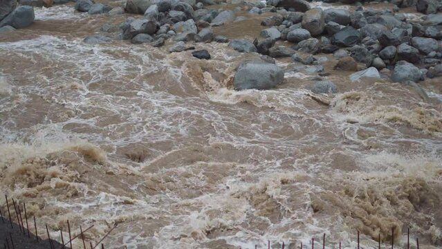 4K shot of Fast flowing raging Beas river after heavy rain in Manali, Himachal Pradesh, India. Soil and mud is moving towards down with water flow. Flooded river in Manali during monsoon season. 