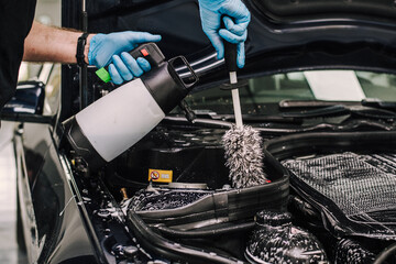 Person wearing gloves cleaning the car engine and interior parts