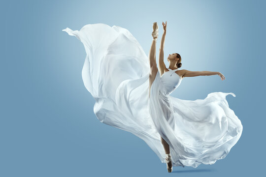 Ballerina doing Split in White flying Dress. Ballet Dancer jumping over Blue background. Freedom and Inspiration Concept. Carefree Beautiful Woman dancing in silk Gown