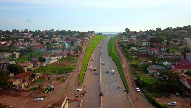 Kampala-Entebbe Expressway, Uganda, East Africa - Vehicles Traveling on the Road Bordering a Residential Area - Drone Flying Forward