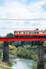 渓谷にかかる赤い鉄橋を走る赤とオレンジの鉄道