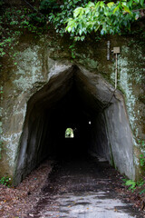 人工的且つ神秘的な暗い手掘りトンネルの入り口と出口に見える人影