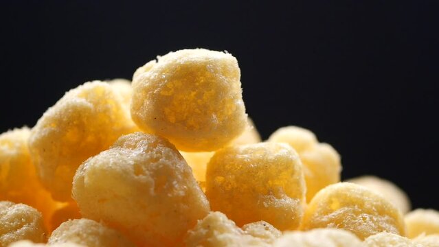 dropping puffed corn rings chips on black background