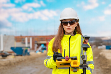 smiling graduate female site engineer surveyor in protective glasses working with theodolite EDM...