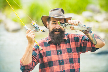 Fisherman caught a fish. Funny man fishing on river. Funny bearded men fisher with fishing rod and net. Fish eye fun.