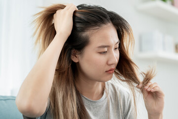 Naklejka premium Asian woman very sad and upset looking at damaged hair, hair loss, hair thinning problem, vitamin deficiency, baldness, postpartum, biotin, zinc, menstrual or endocrine disorders, hormonal imbalance