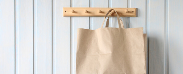 Brown paper bag hanging on a wooden hanger, close-up. Natural background, copy space. Concept: no...