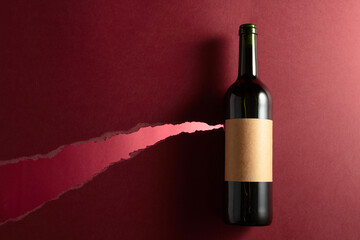 Bottle of red wine with old empty label on a dark red background.