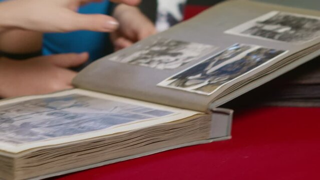 Vintage album with black and white photos. Memories. Old photographs in a vintage album. Relatives look at old photos and postcards. Aged cardboard and yellowish tracing paper in an album. 