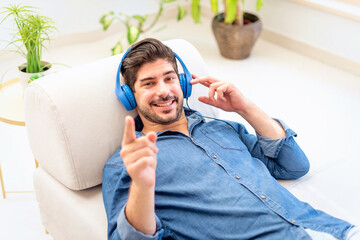 A man with headphone relaxing on the sofa at home and listening to music