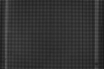 Black perforated metal round holes wall background with light leak.