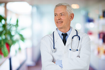 Portrait of an elderly male doctor standing in medical center