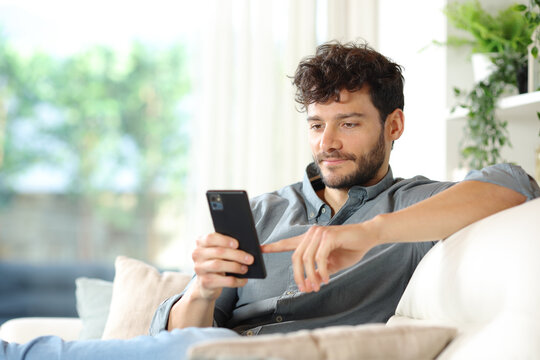 Serious Man Using Phone On A Couch At Home