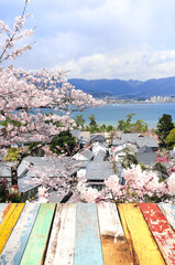 Blank wooden table top and aerial view on sea, houses and blooming sakura trees, Miyajima island, Japan. Traditional japanese hanami festival. Spring cherry blossoming season in Asia