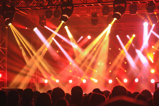 A crowded concert hall with scene stage lights - Powered by Adobe