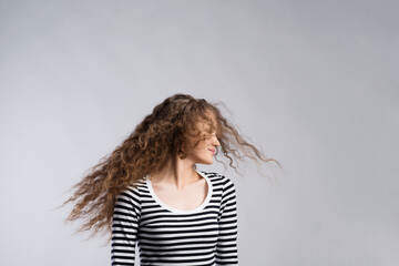 Portrait of a gorgeous teenage girl with curly hair, blowing in wind. Studio shot, white background...