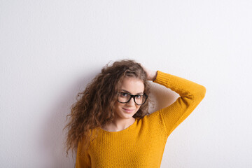 Portrait of a gorgeous teenage girl with curly hair and eyeglasses. Studio shot, white background...