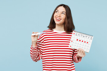 Young fun woman wear red casual clothes hold pregnancy test female periods pms calendar checking menstruation days look aside on area isolated on plain blue background. Medical gynecological concept.