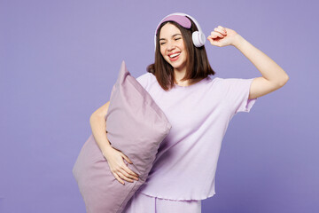 Young calm woman wearing pyjamas jam sleep eye mask rest relax at home listen to music in...