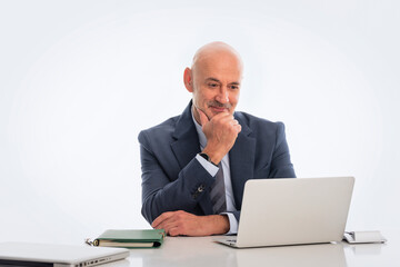 Mid aged businessman sitting at desk and using notebook for work against isolated background