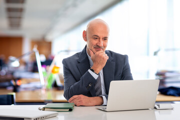 Businessman sitting at the office and looking at the computer thoughtfully