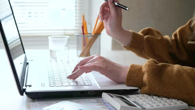Managers work in the office on a computer and calculator with business papers, graphs and diagrams. Female hands of a manager close-up. Slow motion.