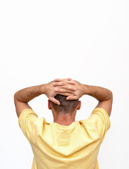 Rear view isolated man in yellow t-shirt standing with his hands behind his head.