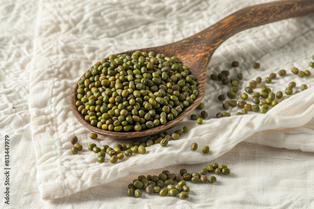 Wall mural mung beans on a wooden spoon over a cloth, depicting natural and healthy food ingredients