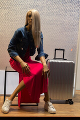 Female mannequin in elegant clothes with a suitcase in a shop window