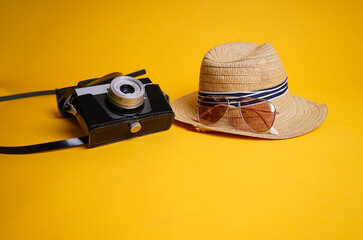 
A straw hat and an old camera on a yellow background