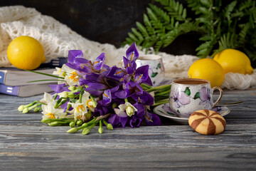 Still life with cups of coffee, field irises and daffodils and lemons close-up