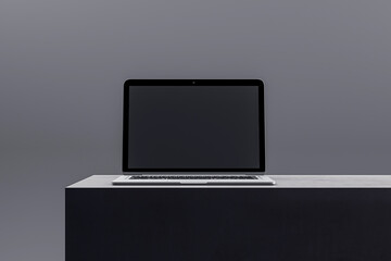 Elegant laptop on a black podium featuring a dark screen, suitable for high-end tech displays and...
