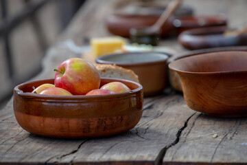 Ripe apples in a ceramic bowl close-up, pottery on a wooden table, medieval lifestyle, still life