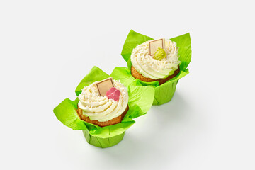 Two cupcakes with whipped cream in green paper wrappers