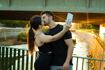 Pareja haciéndose un selfie con el móvil. Enamorados en el rio. Pareja deportista haciendose una...