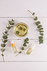 Bowl, bottles of eucalyptus essential oil, bunch of fresh eucalyptus branches. Natural organic...