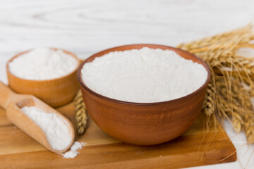 Flat lay of Wheat flour in wooden bowl with wheat spikelets on colored background. world wheat crisis