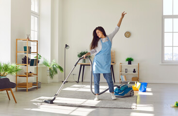 Woman with vacuum in hand, dancing while cleaning floor carpet at home. Image captures the fusion...