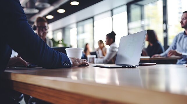 A group of people in business suits in a meeting in a brightly lit office with large windows. Blurred silhouettes of managers and executives.